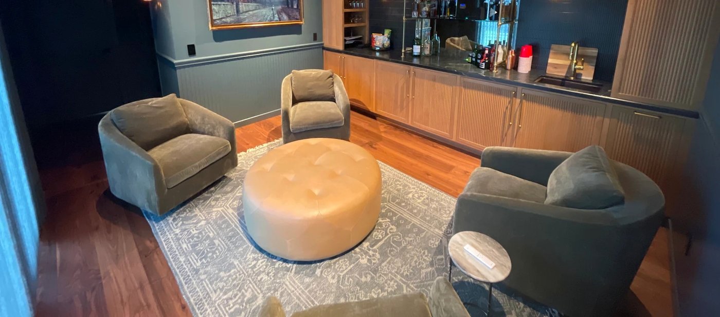 Dark navy lounge with wood wet bar and wainscoting
